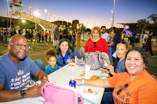 family eating food with stage and booths in the background